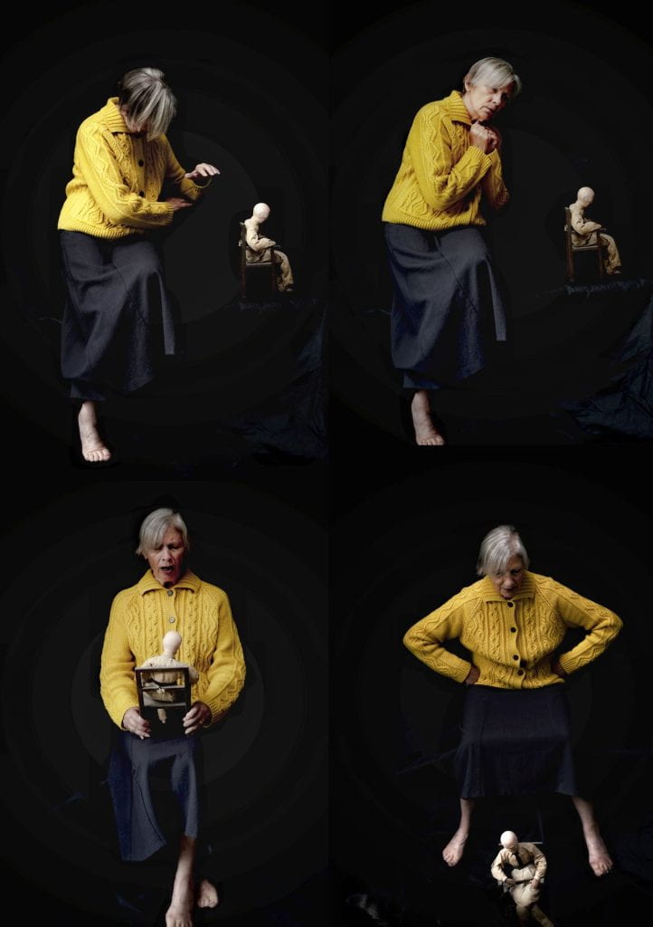 Artwork: Older woman grey hair in yellow cable knit cardigan, dominating a male looking manikin tied to a chair.
